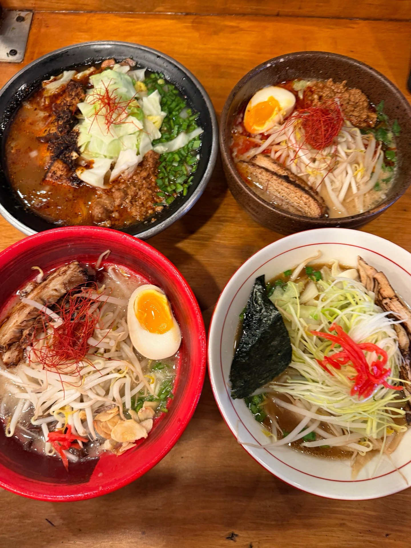 A spread of four Mr. Taka ramen bowls — including Black Tan Tan, Spicy Stamina, and signature broths